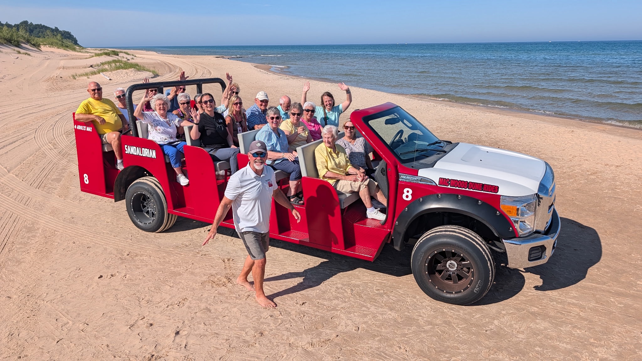 dune ride smv 2026 Image of people on open air truck on sand dunes with water in the background.
